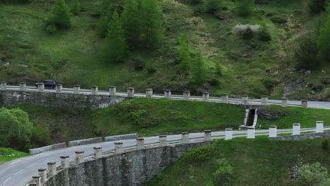 Vista-Aérea-De-Un-Automóvil-Conduciendo-Por-Una-Sinuosa-Carretera-De-Montaña-En-El-Monte-Cenis-En-Francia