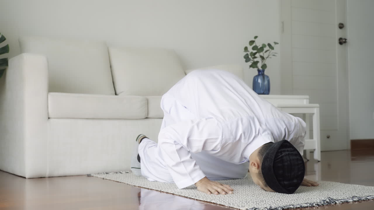 Asian Muslim man reciting surah al-Fatiha passage of the Qur'an, in a daily prayer at home in a single act of sujud called a sajdah or prostration