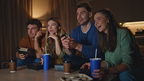 carefree friends discussing tv show at evening living room. mates watching movie