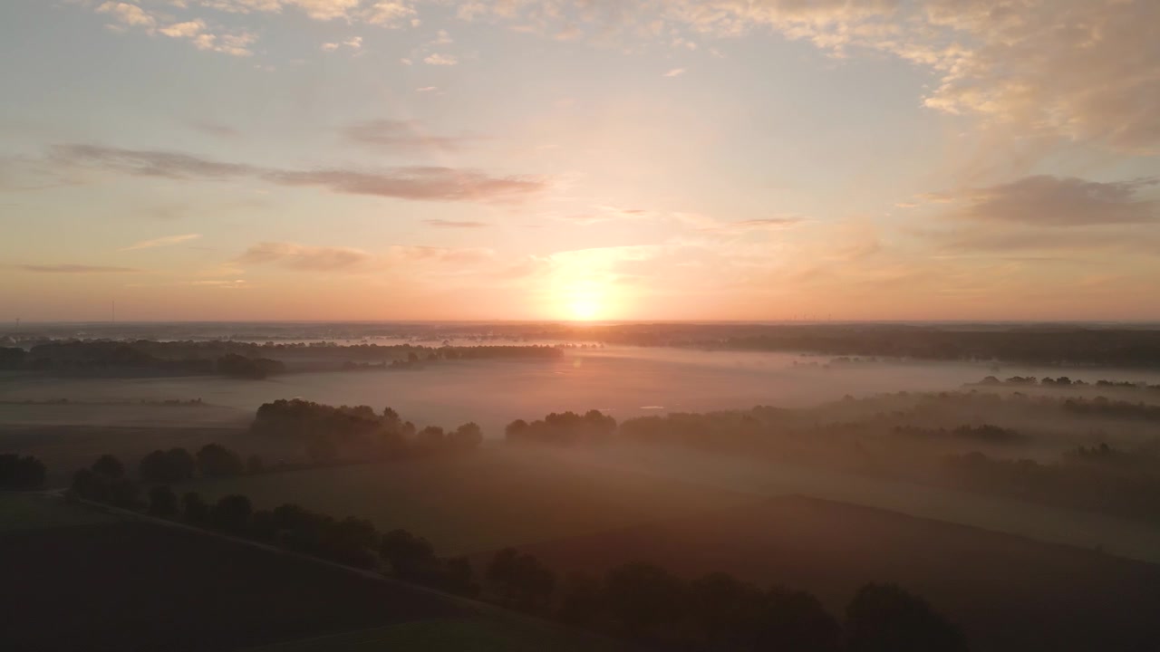 Tåkete skyer omslutter landskapet under soloppgang med gyllent sollys. Bredt luftfoto.