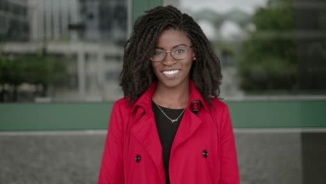 afro-american woman looking at camera, smiling, correcting hair