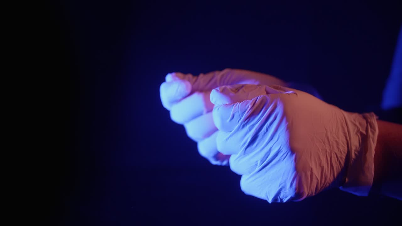 Mani che indossano e tolgono guanti in lattice sotto una luce blu