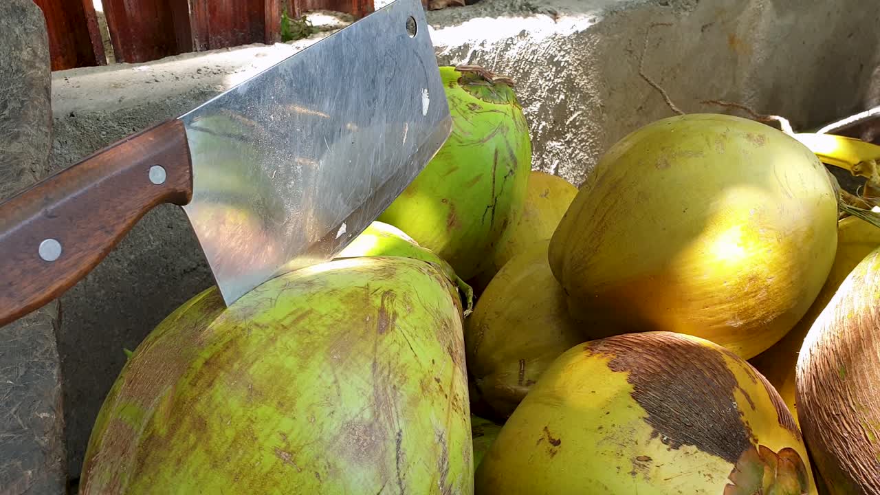 montones de cocos frescos, saludables y deliciosos y un gran machete para abrir, listos para beber agua de coco para saciar la sed, en un remoto destino de isla tropical
