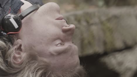 man lying down in a forest with headphones