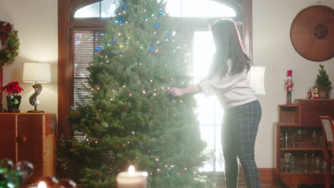woman decorating a christmas tree for the holidays