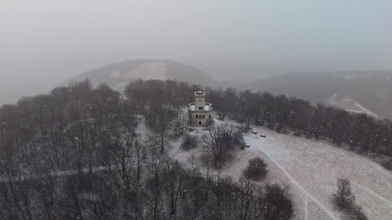 Visegrád, Węgry, wieża widokowa Zsitvay-kilátó na zaśnieżonym wzgórzu w Górach Wyszehradzkich, otoczona bezlistnymi drzewami leśnymi podczas zimowej pogody, widok z lotu ptaka.