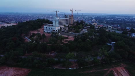 beautiful aerial of the premier hotel in ibadan, nigeria under renovation. the drone slowly flies backwards and reveals the hill the hotel is built on overlooking the city