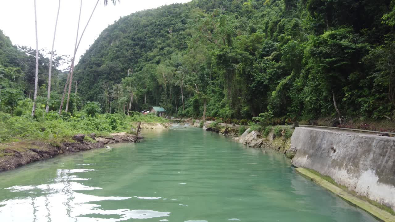 volando bajo sobre el arroyo hacia una cabaña aislada escondida en la exuberante selva tropical