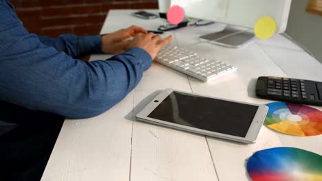 diseñador gráfico masculino usando una tableta digital mientras trabaja en la computadora