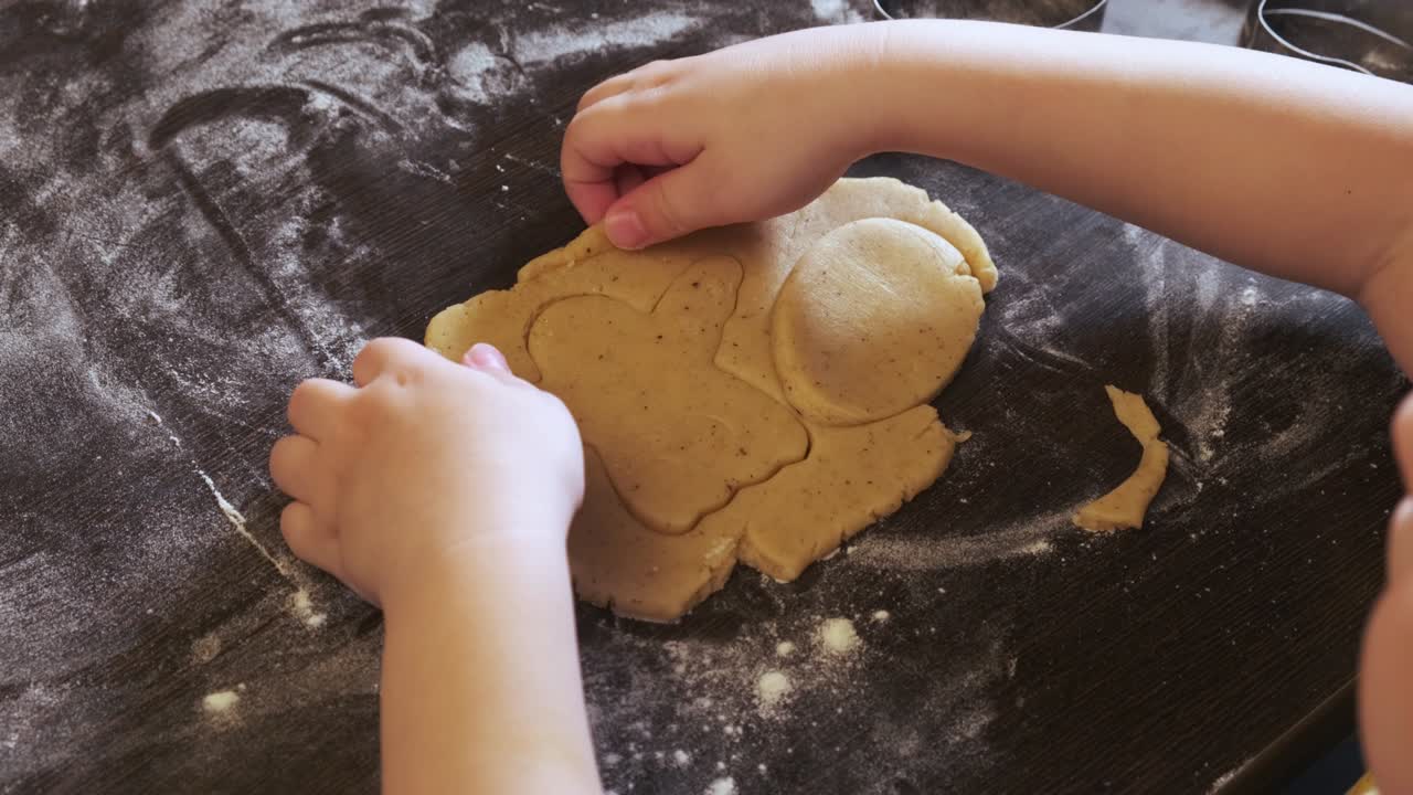 The child's hands are close-up, cookies are cut out of the dough, preparation for Easter