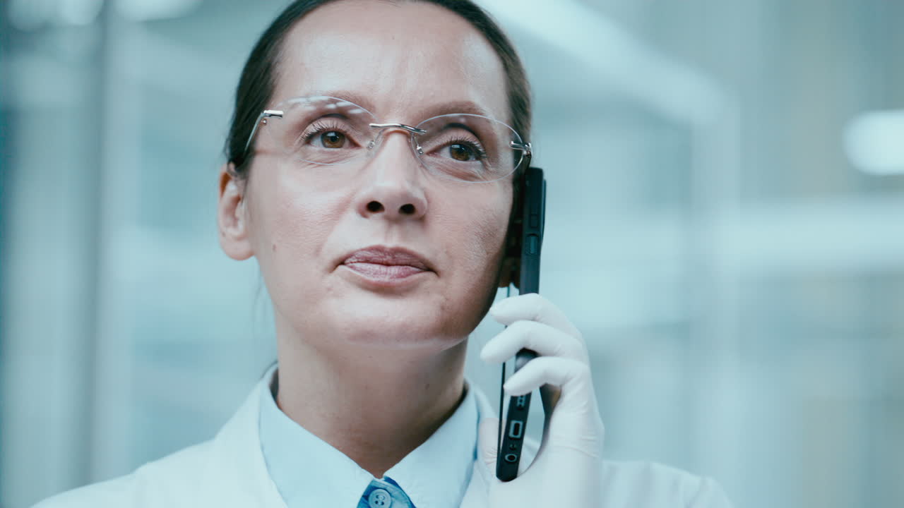Female Scientist in Sterile Gloves Talking on Mobile Phone in Laboratory