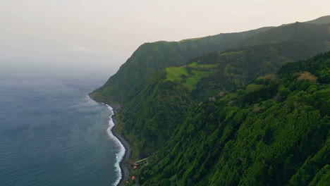 aerial green seashore mountain on cloudy day. dark endless ocean washing coast.