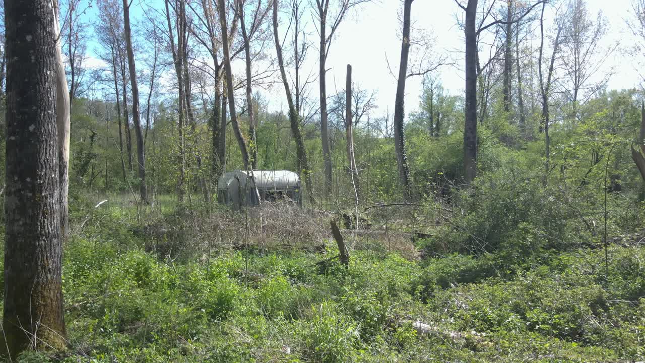 Abandoned caravan entwined by nature's grasp in forest of France,POV