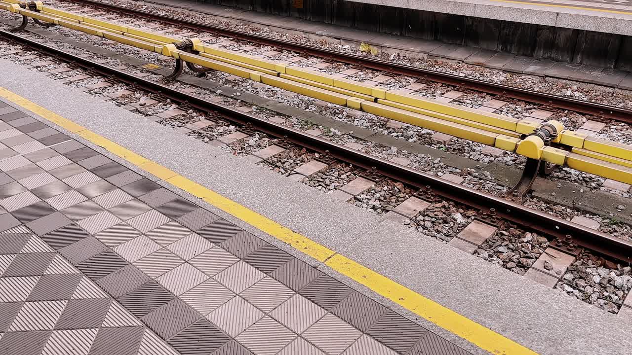 Snow falling on empty railway platform with yellow safety line in Austria
