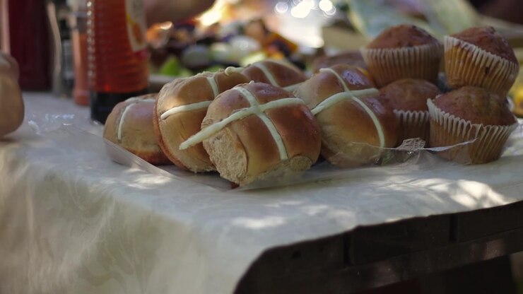 A family sharing a fresh and delicious healthy breakfast outdoors consisting of fruit, hot crossed buns, muffins and more