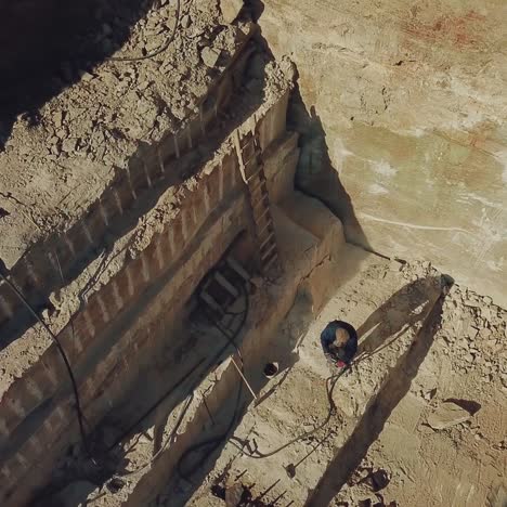 a man is drilling stones with using power tool in a sand quarry. camera motion up