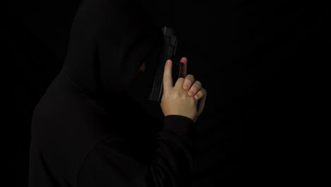 A-hooded-man-with-a-hand-gun-pistol-in-the-dark