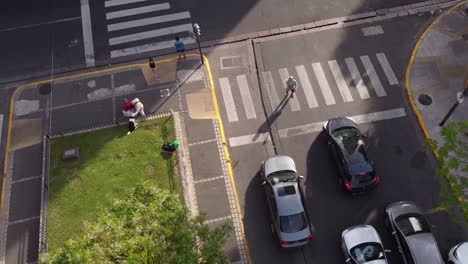 street juggler tossing objects at zebra crossing in front of cars parked at red traffic lights