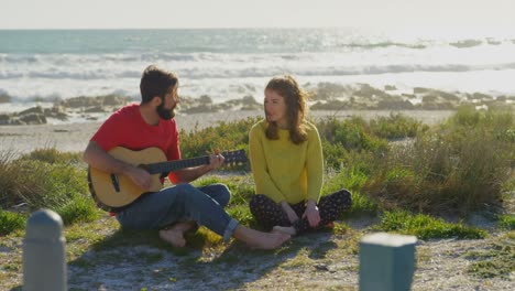 hombre tocando la guitarra para mujer cerca de la playa en un día soleado 4k