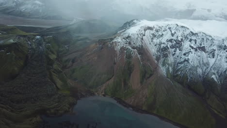 tierras altas de islandia, vista aérea de un paisaje impresionante, nieve en el pico de una montaña volcánica, lago glacial en el valle