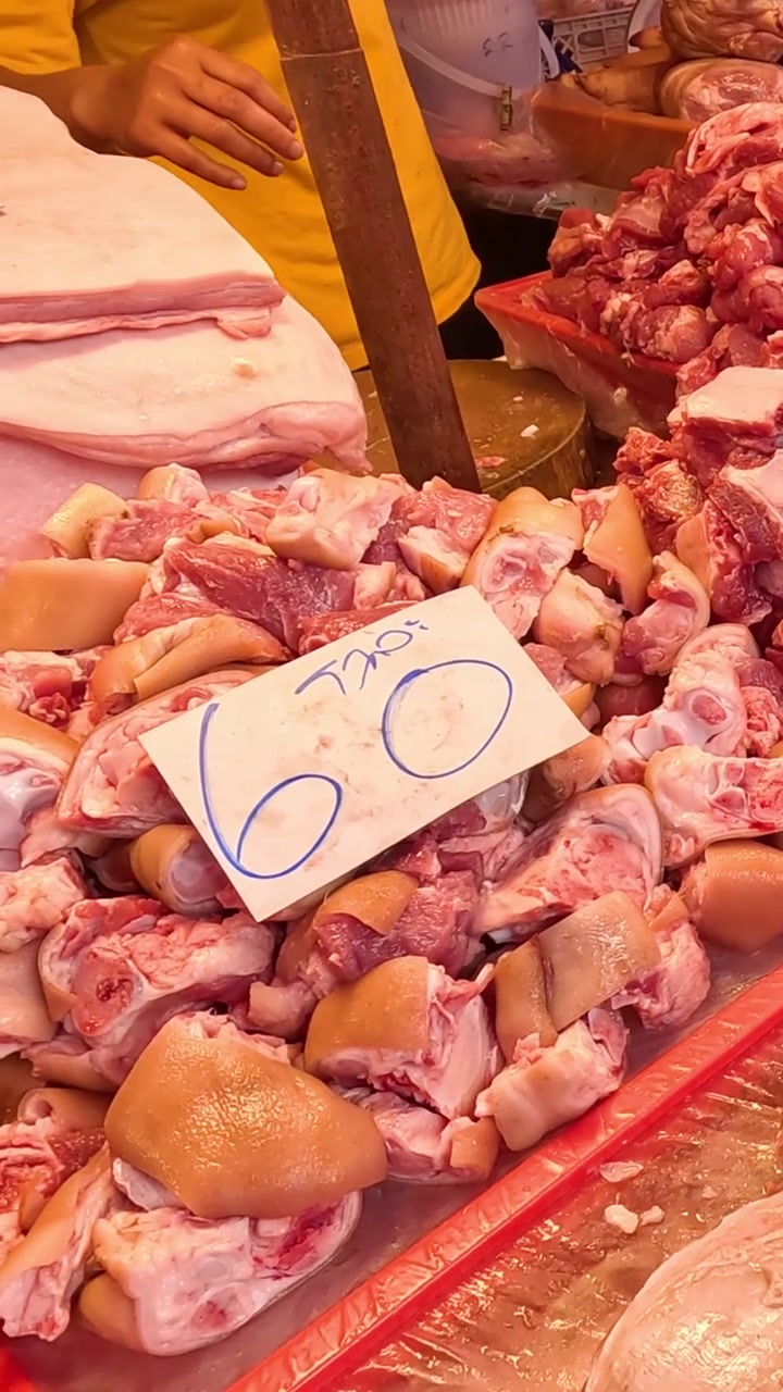 Vertical shot of piles of fresh raw pork with price tags displayed at a market.