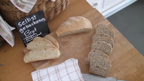 Fresh-whole-grain-bread-and-white-bread-lying-on-a-wooden-table-with-a-knife-and-a-towel-laying-besides