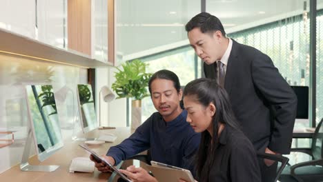 three business people having meeting together with boss discussing the charts and graphs showing the results