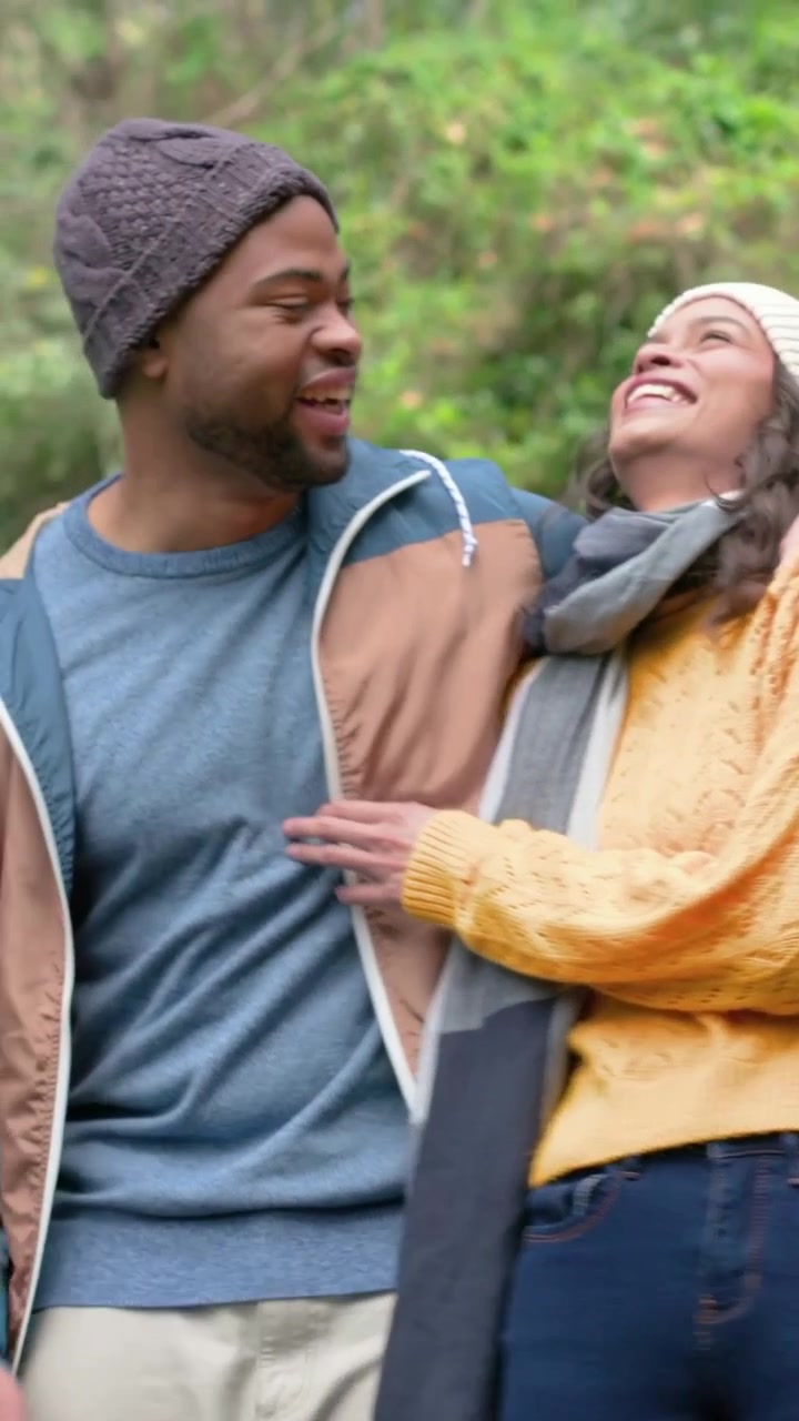 Vertical video: Deciding to walk, couple strolling narrow trail to spend time, wearing knit beanies