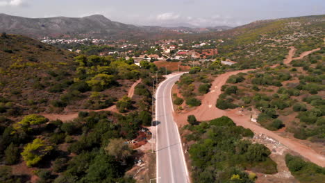 Silver-bus-driving-on-road-at-Cape-Sounion,-forward-aerial