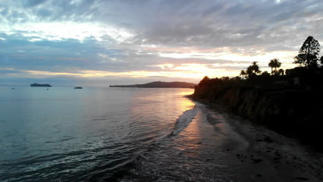 aerial drone shot at sunset overlooking the pacific ocean and california cliffs of santa barbara from butterfly beach in montecito