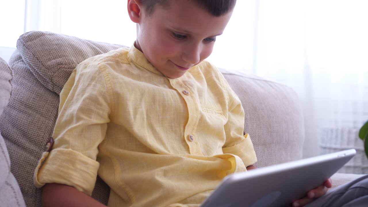 un niño guapo usando una tableta en casa.