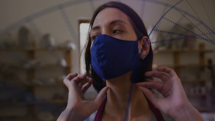 Woman artisan seeing blue specks appearing in foreground, putting blue mask to protect craftwork