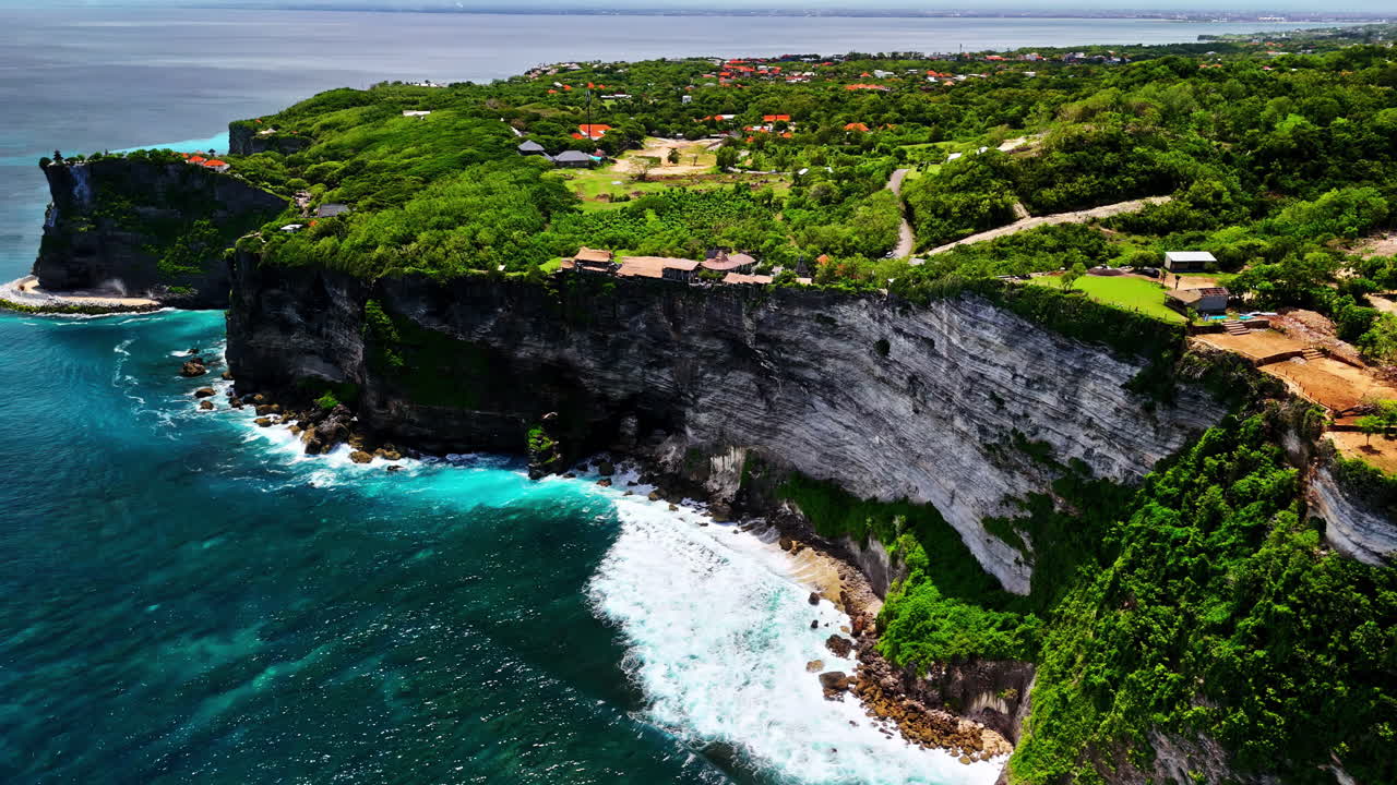 An impressive aerial view of Nyang Nyang Beach, showcasing dramatic high cliffs, vibrant turquoise waters, and lush green vegetation along the stunning coastline
