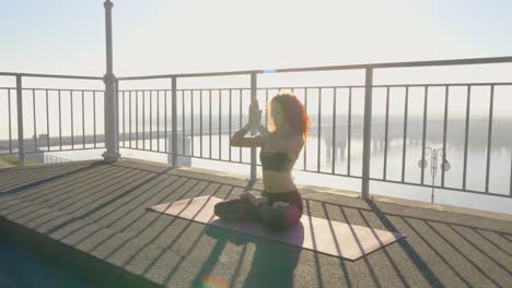 woman practicing yoga on rooftop with river view