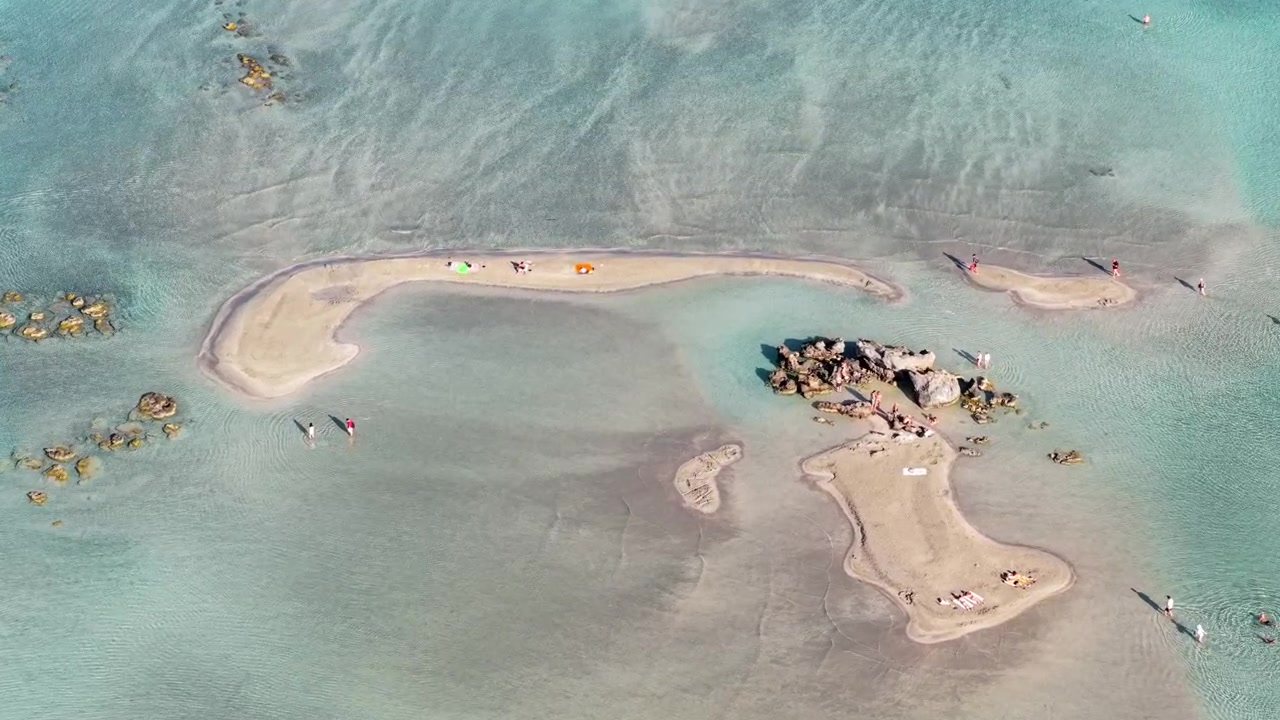 Luftfoto fra drone ovenfra af sandbanker og en klynge klipper i den lavvandede turkise lagune med folk, der vader, Elafonissi, Grækenland