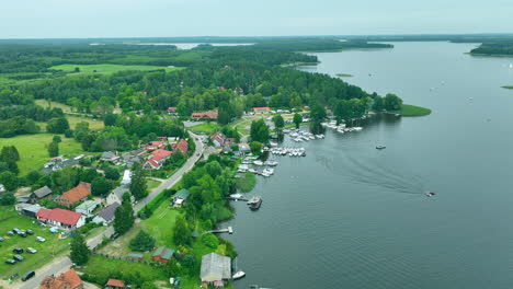 lakeside view with houses, trees, and boats along the shore under an overcast sky