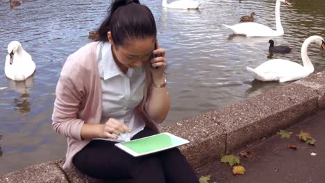 Businesswoman-using-her-phone-and-tablet-outside