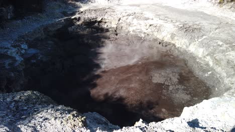 steam above small natural pool in active geothermal waiotapu area, new zealand