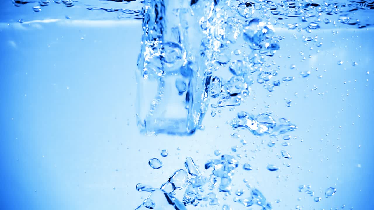 Ice cubes dropped into water with air bubbles.