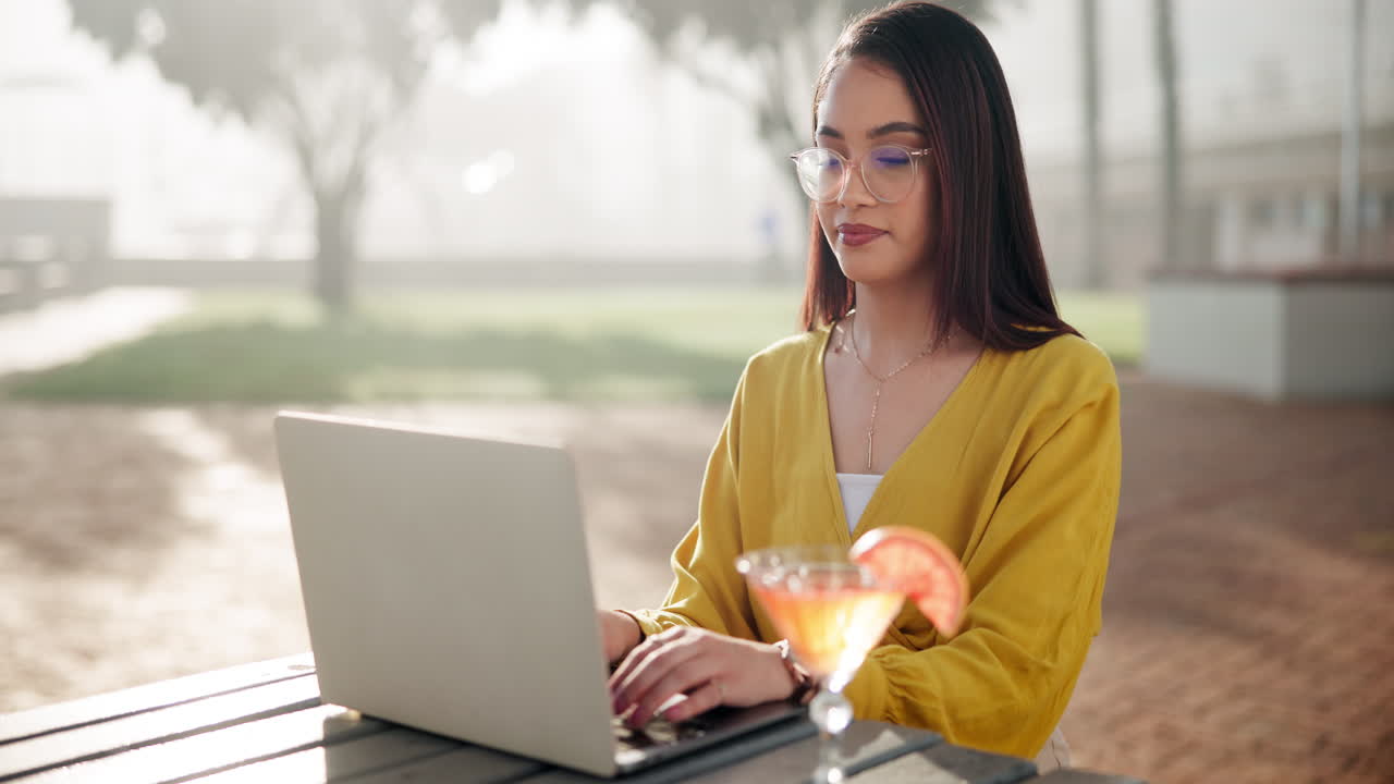 Woman working on laptop with cocktail