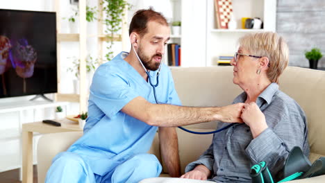 Médico-Masculino-Caucásico-En-Un-Hogar-De-Ancianos-Escuchando-Los-Latidos-Del-Corazón-De-Una-Anciana