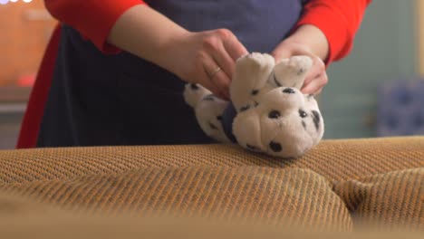 mujer limpiando un sofá con un perro dalmático de peluche