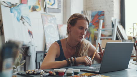 woman artist working on a laptop in an art studio