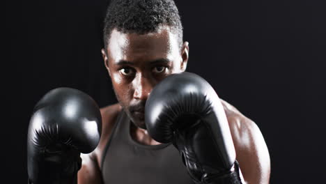 focused african american boxer training in a dark gym on a black background