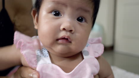 adorable baby girl in a pink bow, sitting happily on a lap, focused on playing and exploring with a cheerful attitude. capturing a heartwarming moment of healthy infant development.