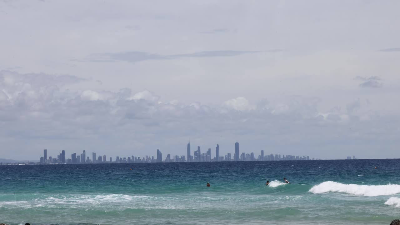 Surfers ride waves with city skyline view