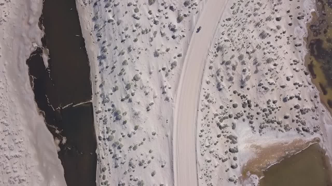 희박한 불모의 사막 도로를 통해 운전하는 오토바이 라이더 위의 조감도