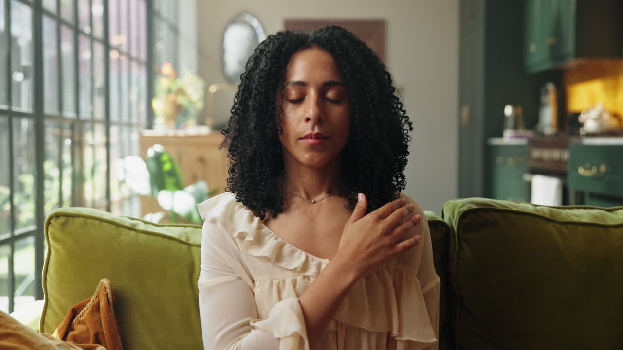 Young Woman Meditating Peacefully on a Sofa at Home