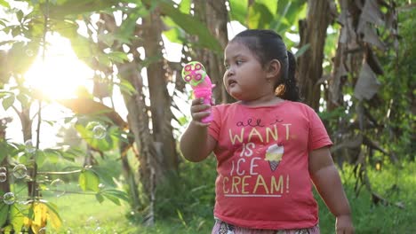 niño asiático jugando con una pistola de burbujas, en cámara lenta