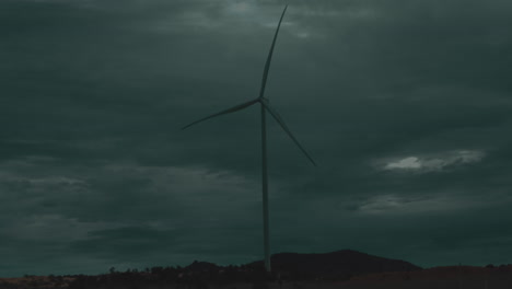 Medium-view-of-single-wind-turbine-spinning-above-grassland-plain-on-stormy-day